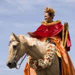 photo of a lady wearing a red cape on a horse